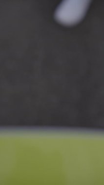 Dinamik bir yakın çekim, parlak yeşil alan yüzeyinde bir futbol ayağının tam hareket halinde olduğunu gösteriyor.