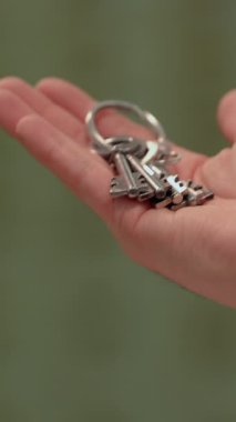 Yumuşak ve bulanık bir arkaplana karşı konumlandırılmış bir anahtarlık setini nazikçe tutan bir el