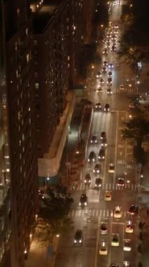 Hava görüntüsü, trafik ışıkları ve enerjik kentsel etkinliklerle dolu hareketli bir şehir caddesini gösteriyor.