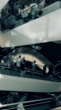Yürüyen merdivenlerde yürüyen insanlarla dolu hareketli bir alışveriş merkezi, gerçekten canlı şehir hayatı sergiliyor.
