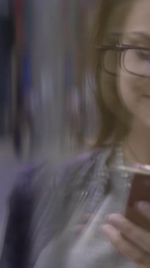 Şık giyimli bir kadın, modern yaşam tarzını ve teknolojisini sergileyen şık akıllı telefonuyla gelişigüzel etkileşime giriyor.