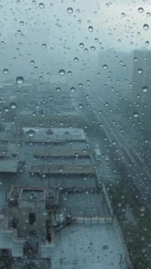 Şehir manzarasının güzel sisli bir görüntüsü camdaki yağmurla kararır ve canlı şehir atmosferini yakalar.