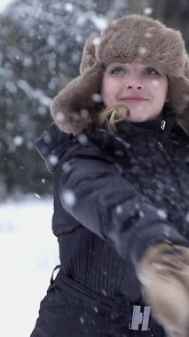 Neşeli ve neşeli bir birey, kış harikalar diyarının tadını çıkarırken neşe içinde bir kartopu atmaktan zevk alıyor.