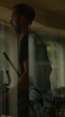 Kendini adamış bir adam eliptik bir eğitmen üzerinde gayretle egzersiz yapıyor. Forma ve sağlığa olan bağlılığını gösteriyor.