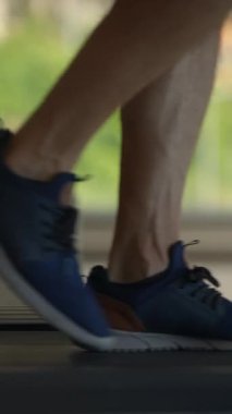 Koşu bandında hareket eden bir bacağın odaklanmış görüntüsü, spor ayakkabıları ve spor etkinliği sergileniyor..