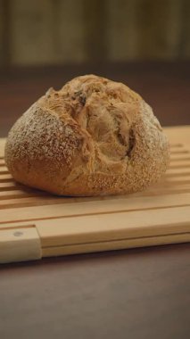 Çok güzel işlenmiş bir somun ekmek kırsal kesim tahtasının üzerinde zarif bir şekilde dinleniyor ve cazibesini gösteriyor.