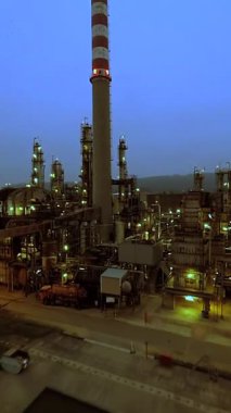 Alacakaranlıkta parlayan aydınlık yapıların yer aldığı endüstriyel bir fabrikanın nefes kesici görüntüsüne tanık olun.
