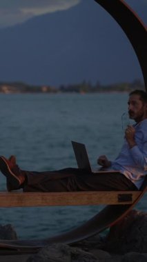 Büyüleyici bir alacakaranlık sırasında uzak çalışma ve deniz kenarında dinlenmenin özünü yansıtan sakin bir sahne.