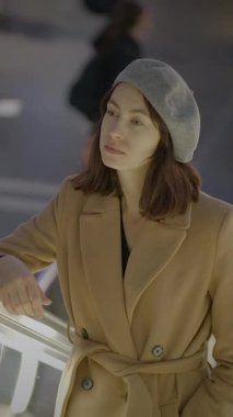 Şık bir kadın düşünceli bir şekilde gökyüzüne bakıyor, modern ve şık sonbahar kıyafetlerini sergiliyor.