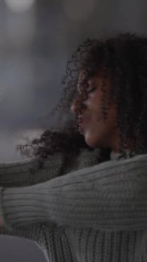 Kendine güveni tam, güzel kıvırcık saçlı bir kadın cazibesini modern bir şehir ortamında sergiliyor.