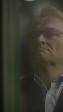 Derin düşüncelere dalmış bir figür, düşünceli bir şekilde uzaklığa bakıyor, cam camlardan hafifçe aydınlatılıyor.