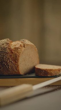 Zanaatkar tam tahıllı ekmek dilimlenmiş ve kırsal ahşap bir tahta üzerinde sunulmuştur. Mutfak görselleri için mükemmeldir..