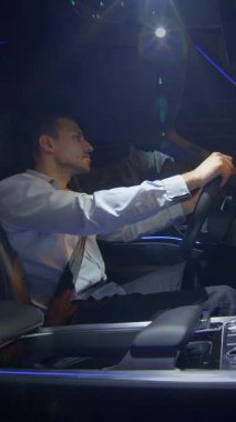 Resmi giyinmiş bir işadamı lüks arabasıyla gece boyunca canlı bir şehirde gezer ve başarısını gösterir.