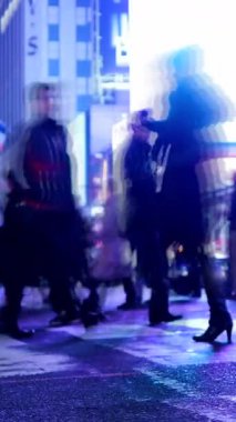 Bulanık ve belirsiz bir görüntü gece canlı ve canlı bir şehir caddesinden geçen sayısız yayanın