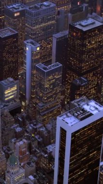 Havadan çekilen bir fotoğraf alacakaranlık gökdelenlerine karşı aydınlanmış gökdelenleri gösteriyor, canlı ve canlı bir şehir manzarasını vurguluyor.