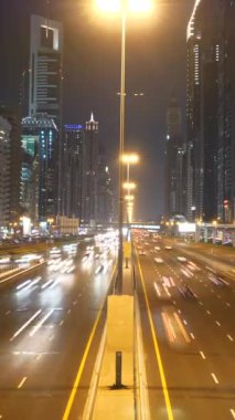Geceleri, modern mimari ve enerjik bir atmosferle parlayan hareketli bir şehir otoyolunu gözlemleyin.