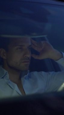 Düşünceli ve düşünceli bir adam, yumuşak ve loş bir ışığın altında rahat bir şekilde otururken derin bir şekilde yansıtıyor.