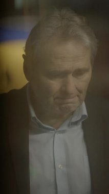 Orta yaşlı bir adam derin bir yansımada kaybolur. Yumuşak ve yumuşak bir ışıkla güçlendirilmiş bastırılmış bir atmosferle çevrili.