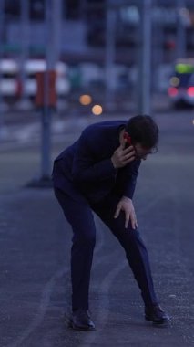 Şık takım elbiseli iyi giyimli bir adam alacakaranlıkta neşeli bir şekilde dışarıda kutlama yapar. Mutluluk ve özgürlüğün vücut bulmuş halidir.