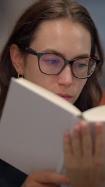 Genç bir kadın, dikkate değer konsantrasyonunu ve merakını sergileyerek, ilgi çekici bir kitap okumaya dalmıştır.