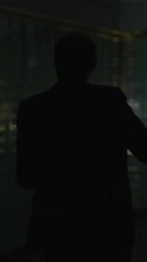 Karanlık bir figür, loş ışıkta gizlenmiş, hapisane parmaklıklarının arkasında belirsizlik ve entrika hissi yaratıyor.