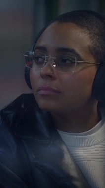 Düşünceli ve düşünceli bir genç, gözlük takan, kulaklık takarken derin düşüncelere dalıyor.