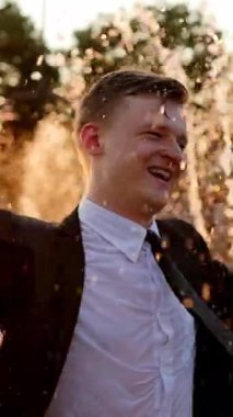 Genç bir adam sersemletici bir fıskiyenin önünde güzel bir anın tadını çıkarırken yürekten ve mutlulukla gülüyor.