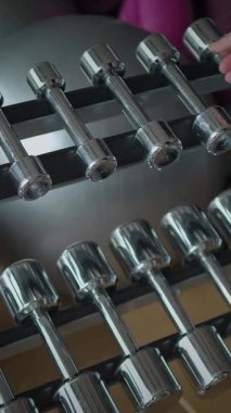 Mükemmel bir sıra parlak krom halterler titizlikle bir spor salonunun rafında dizilmiştir.