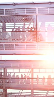 Güneş batarken çarpıcı manzaranın tadını çıkaran insanlarla dolu modern cam bir yapı.