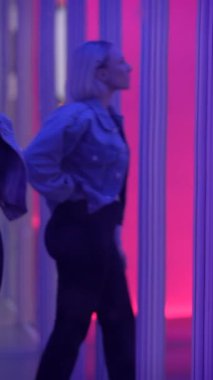 Modaya uygun bir birey, canlı neon ışıklarla süslenmiş şık çağdaş bir ortamda güven içinde duruyor.