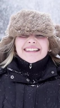 Keyifli bir çocuk, etraflarına kar yağarken, rahat bir kürk şapka ve kışlık palto giyerek neşe saçar.