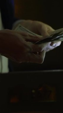 Para transferlerinin önemini vurgulayan, loş bir ayarda dolarları sayan ellerin yakınlaşması