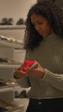 Bir kadın ilginç bir şekilde modern bir perakende mağazasında şık ayakkabıları inceliyor. Benzersiz moda ürünleri sergiliyor.