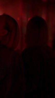 Siluetli figürler kırmızı ışıkta aydınlatılıyor, entrika ve şehir gece hayatının özünü çağrıştırıyor.