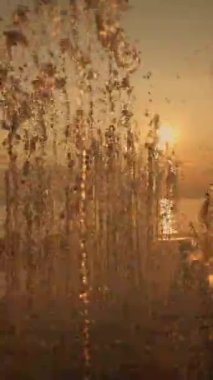 Görkemli bir su çeşmesinin arkasında nefes kesici bir günbatımı, sakin, rüya gibi bir atmosfer yaratıyor.