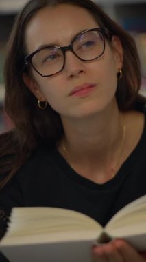 Derin düşüncelere dalmış, tamamen kitap okumaya dalmış sakin bir kütüphane ortamını yansıtan biri.