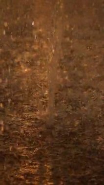 Dokulu bir yüzeyde parıldayan yağmur damlalarının yakın çekimi, su yansımalarının güzelliğini yakalıyor..