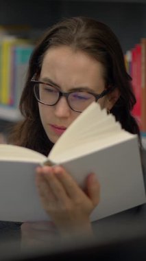 Büyüleyici bir kitapla büyülenmiş genç bir kadın edebiyata olan bağlılığını bir kütüphanede sergiliyor.