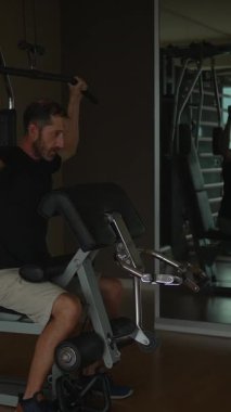 Bir adam şu anda modern ve iyi donanımlı bir spor salonunda yoğun bir çalışma yapıyor.