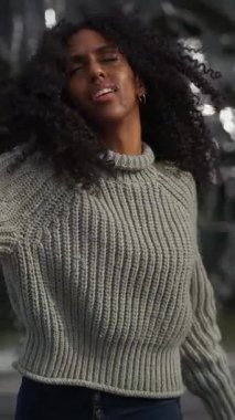 Sıcak ve rahat bir süveter giymiş neşeli bir insan, kışın etrafını saran bir yerde anlamlı bir şekilde el kol hareketi yapıyor.