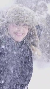 Bir insan, güzel bir kış manzarasında neşeyle dolu ve düşen güzel kar taneleriyle oynuyor.