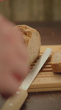 Keskin bir bıçağın yanında, kırsal kesim tahtasının üzerinde duran kahverengi bir somun ekmek yemek fotoğrafçılığı için mükemmeldir.