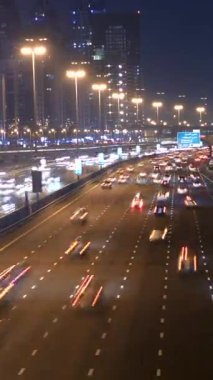 Modern bir otoyolda hareketli şehir trafiğini gösteren dinamik ve canlı bir gece manzarası yaşayın.