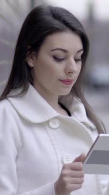 Genç bir kadın yoğun bir şekilde tabletine odaklanmış, kentsel bir ortamda çağdaş dijital etkileşim sergiliyor.