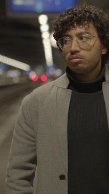 Düşünceli ve düşünceli genç bir birey, büyüleyici gece saatlerinde canlı bir şehir ortamında.