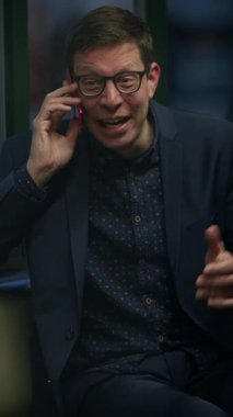Şık giyinmiş genç bir adam telefonuyla sohbet ediyor, neşeli bir anın tadını çıkarıyor.