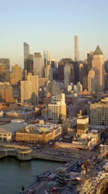 Günbatımında gökyüzüne yükselen hareketli bir şehrin çarpıcı hava manzarası modern mimari ve limanı sergiliyor..