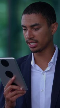 Bir tablet cihazı kullanan odaklanmış bir işadamı, modern teknolojinin iş yerindeki rolünü etkili bir şekilde gösteriyor.