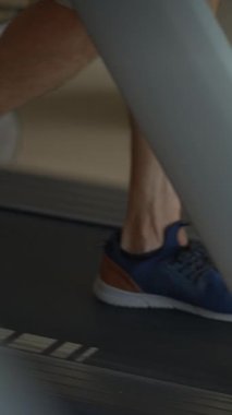 Koşu bandında hareketli spor ayakkabılarının yakın çekim ve odaklanmış görüntüsü, spor salonu uygunluğu ve egzersiz.