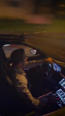 Yetenekli bir sürücü geceleri hareketli şehir sokaklarında modern araba teknolojisi ve şehir yaşam tarzını sergiliyor.